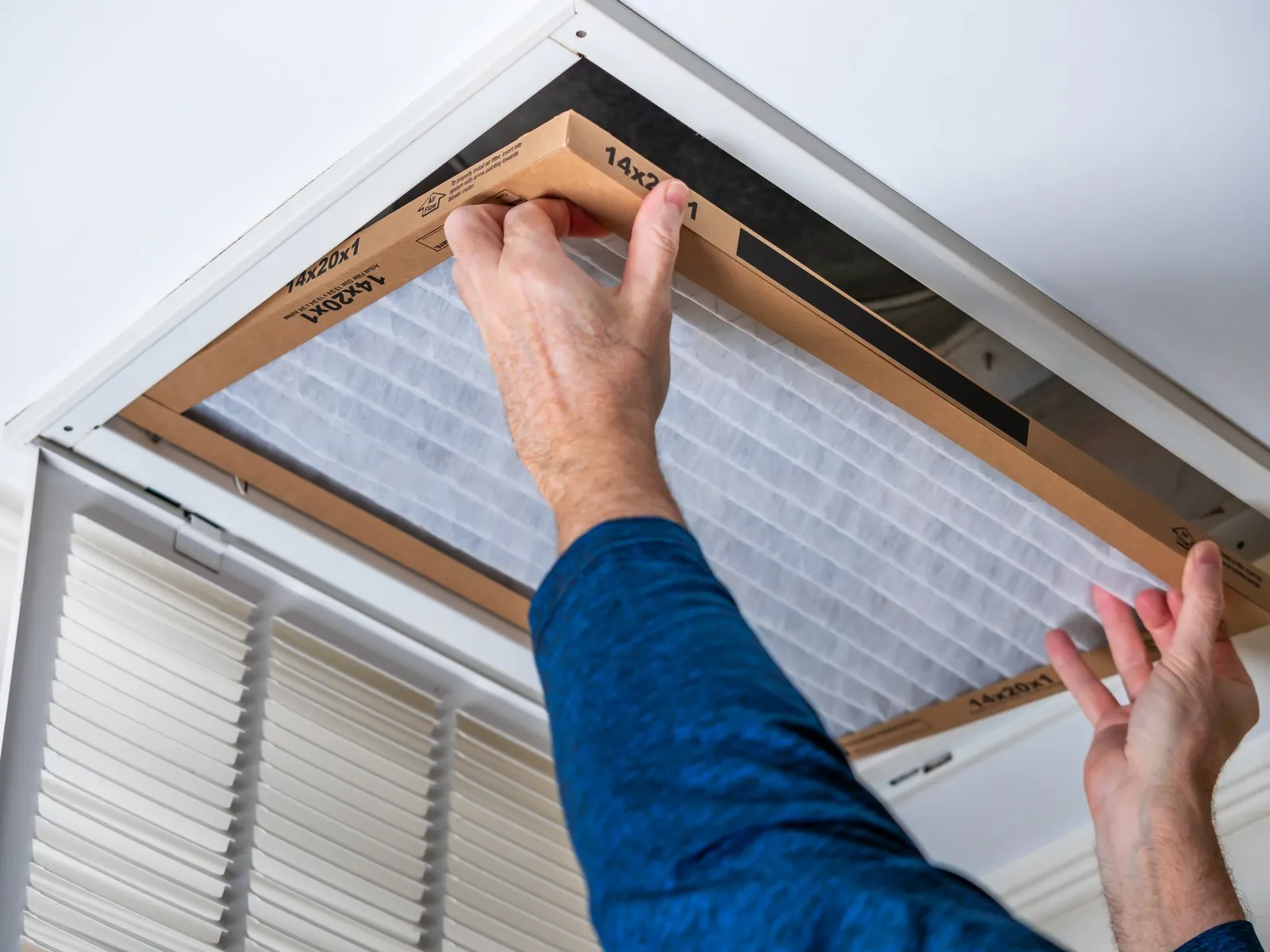 Illustrative stock photo — a technician replacing a home HVAC air filter; not an actual Lake Havasu AC Guide job site.